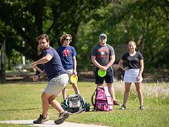 学生 playing disc golf on campus.